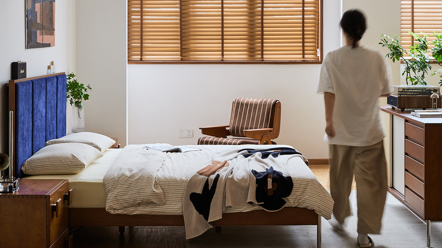 Cozy bedroom with blue velvet headboard and wooden furniture, representing Loft Home’s 30-day return and refund guarantee for a worry-free shopping experience.