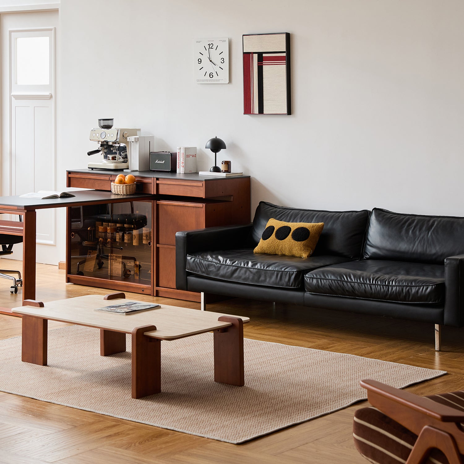 Modern living room with black leather sofa, wooden coffee table, and kitchen area.